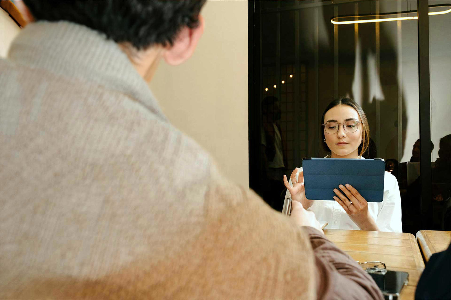 Frau nutzt Tablet, Büroraumszene im Kontext digitaler Belastung und EMF-Schutz.