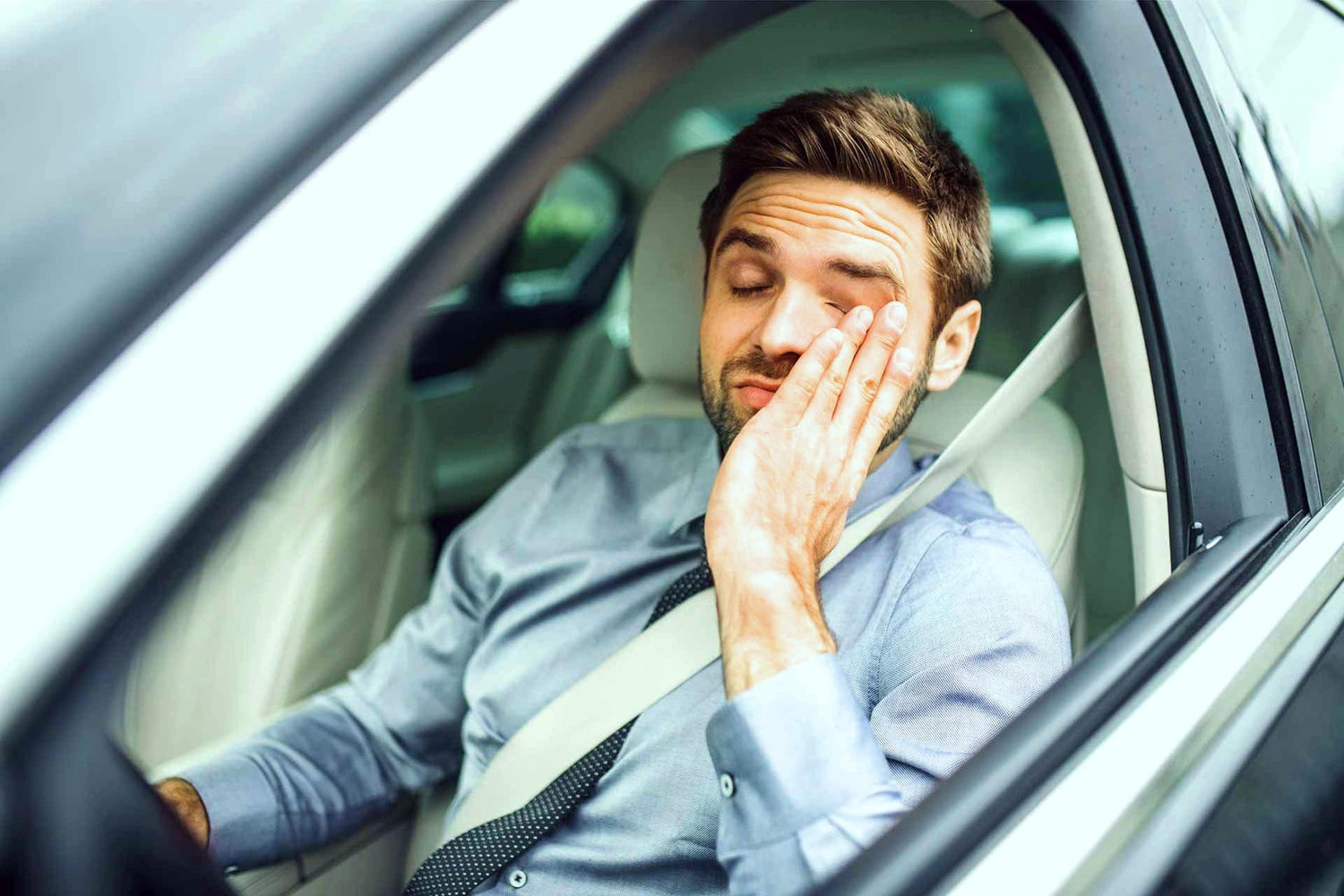 Mann sitzt müde im Auto und reibt sich die Augen – Alltagssituation im Kontext von Elektromobilität und elektromagnetischer Belastung.