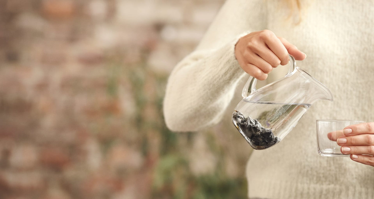 Steine Arielle aus EssenceX-Edelschungit von Beyond Matter in einem mit Wasser befüllten Wasserkrug.