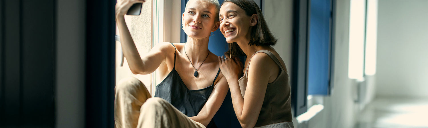Lächelnde Frauen mit Smartphone – Sinnbild für Gemeinschaft, Partnerschaft und Affiliates mit Beyond Matter.