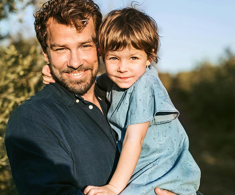 Vater hält sein Kind im Arm – Sinnbild für Vertrauen, Nähe und ein sicheres Gefühl im Alltag.