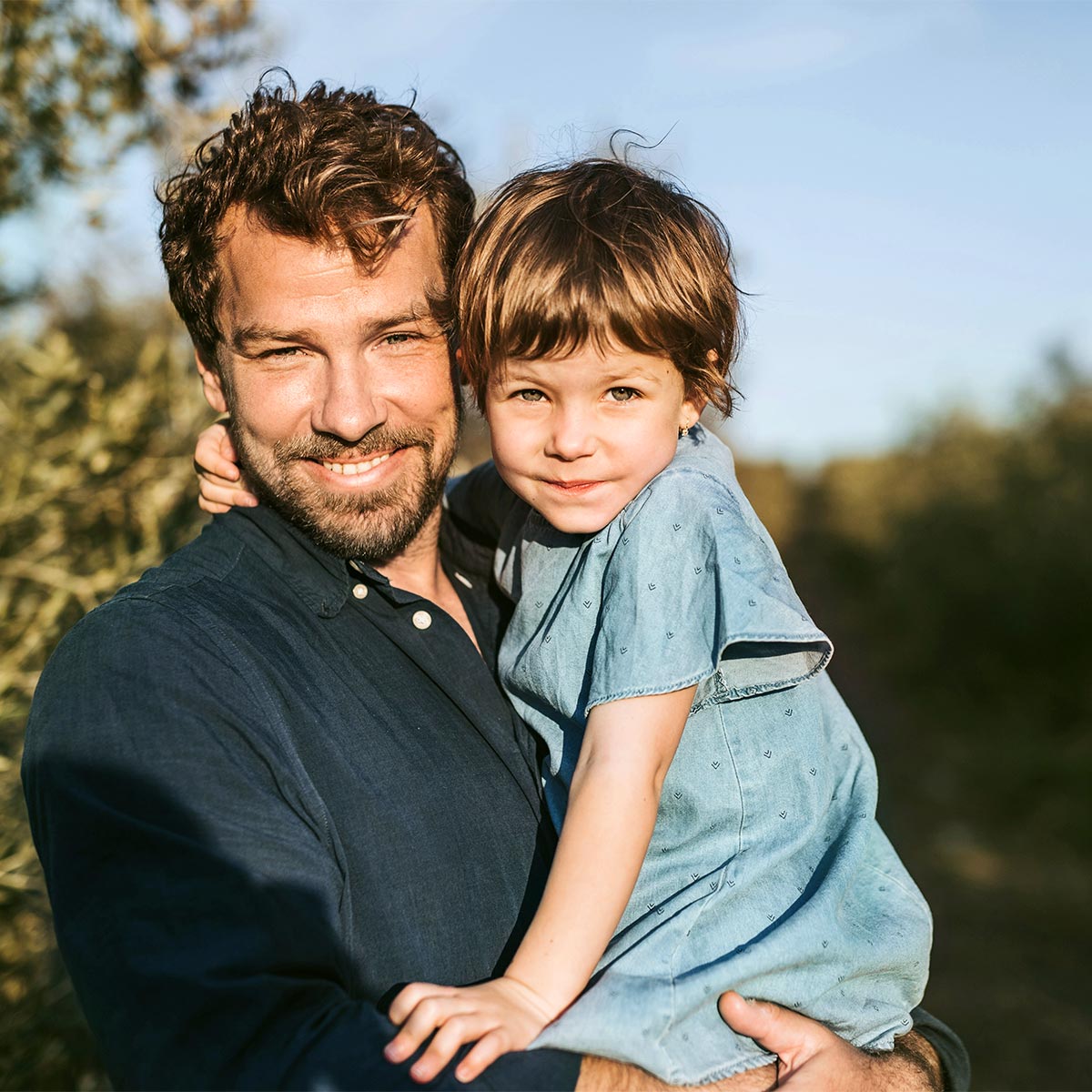 Vater hält sein Kind im Arm – Sinnbild für Vertrauen, Nähe und ein sicheres Gefühl im Alltag.