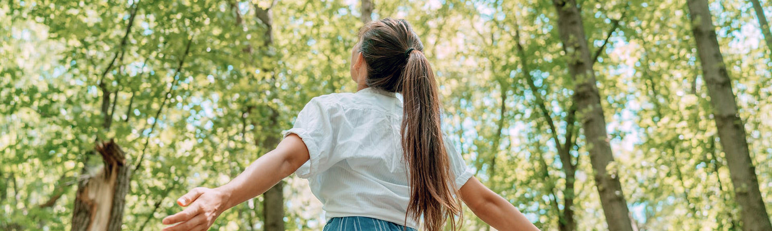 Frau mit ausgebreiteten Armen im Wald – Sinnbild für Freiheit, Zukunft und natürliche Verbundenheit mit Beyond Matter.