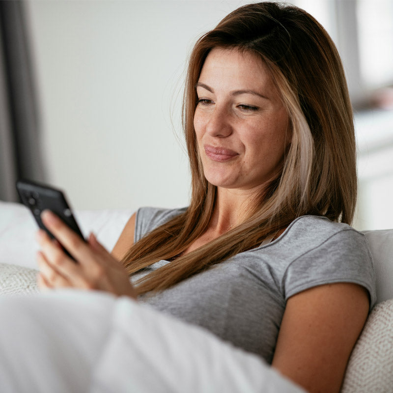 Frau nutzt Smartphone – Sinnbild für bewussten Umgang mit Elektrosmog und EMF-Schutz im Alltag.