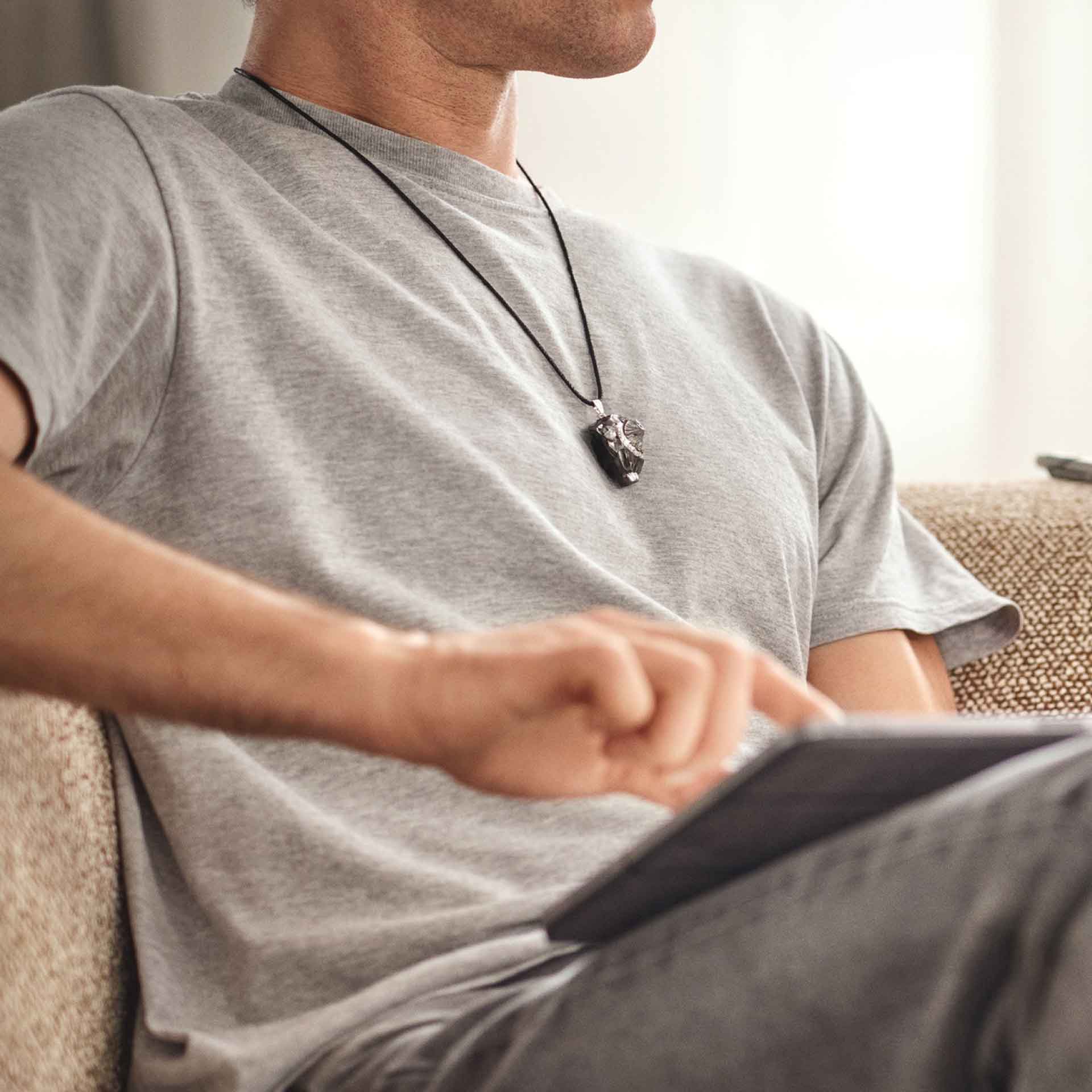 Anhänger an einer Kette am Körper getragen – auf Herzhöhe, getragen im Alltag.