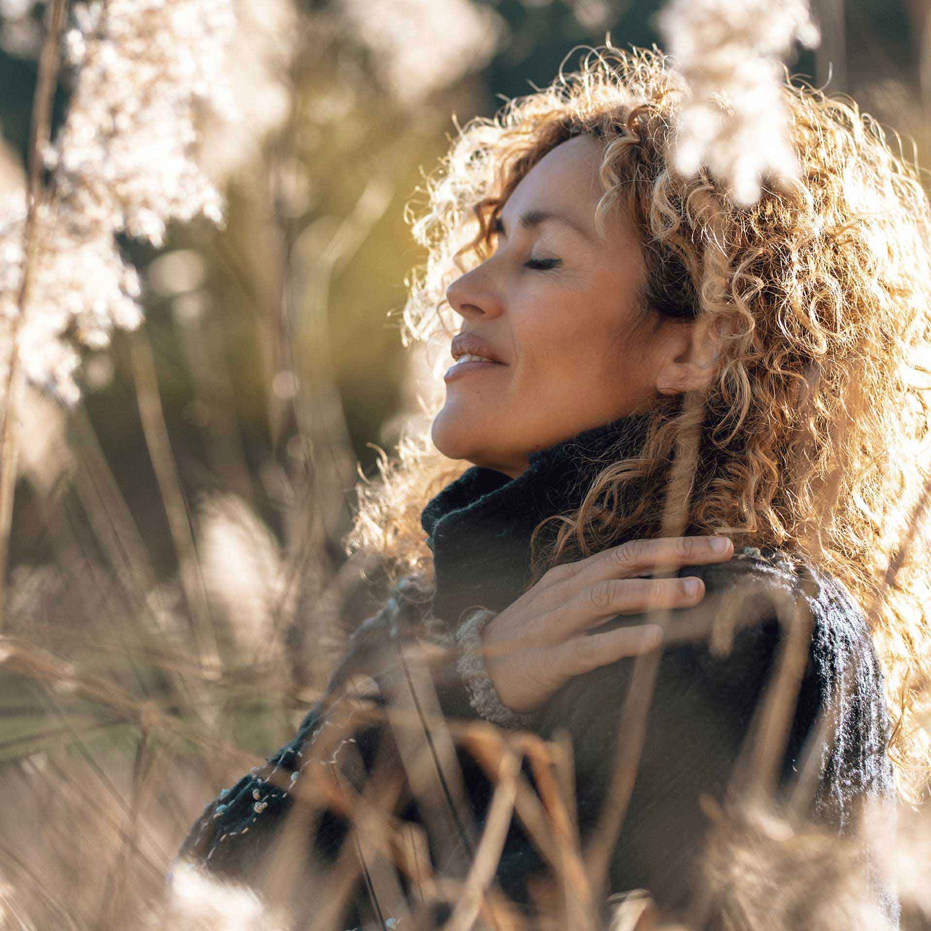Frau in der Natur mit geschlossenen Augen – Sinnbild für Erdung, Ruhe und neue Energie.