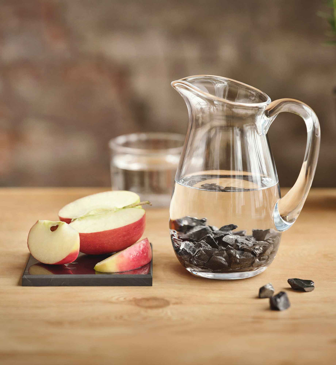 Steine Arielle aus EssenceX-Edelschungit von Beyond Matter in einem mit Wasser befüllten Wasserkrug.