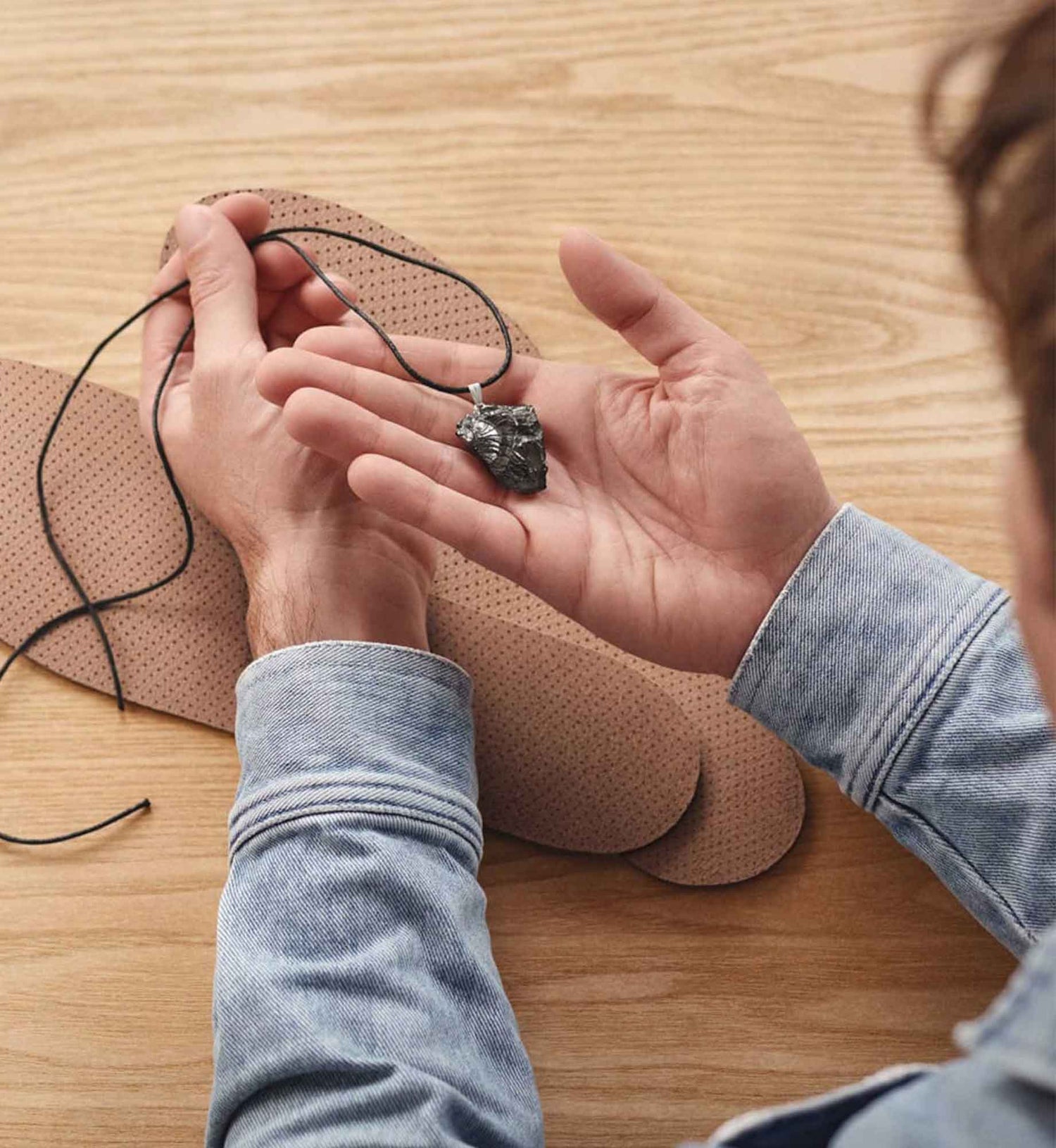 Unboxing-Situation des Beyond Matter Essentials-Sets: Ein Anhänger wird in der Hand gehalten, die Einlegesohlen liegen auf dem Tisch.