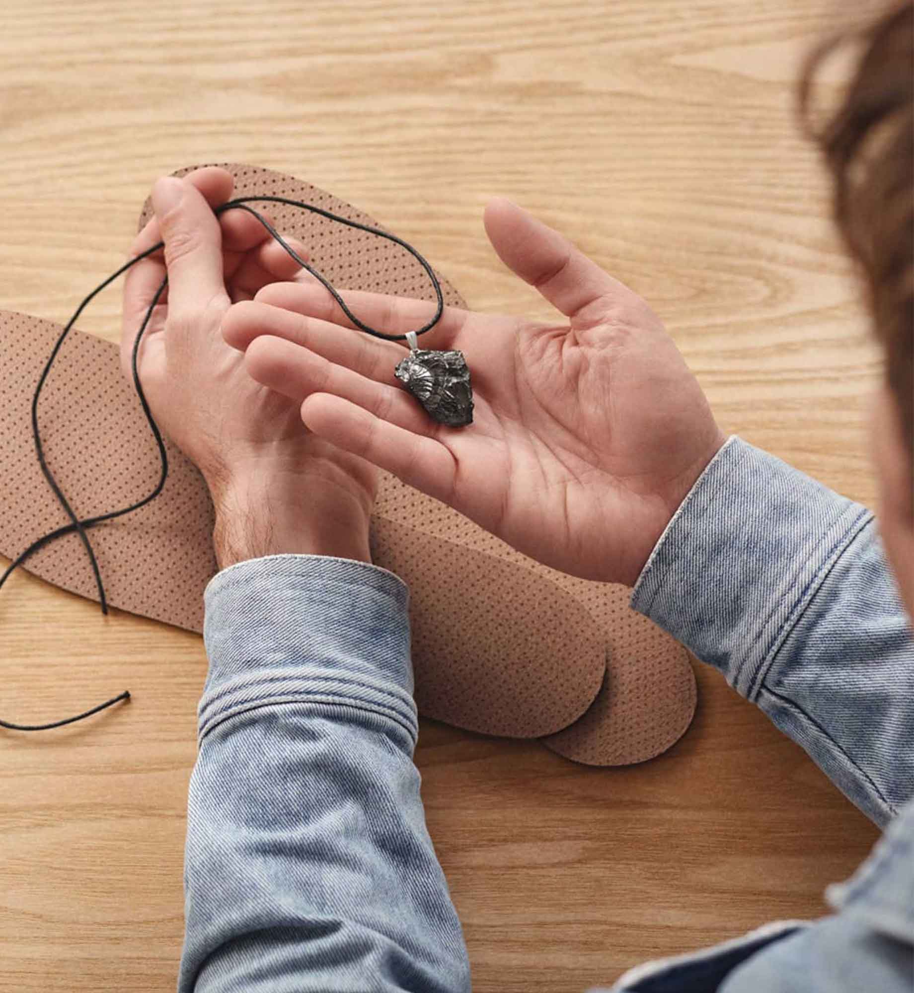 Unboxing-Situation des Beyond Matter Essentials-Sets: Ein Anhänger wird in der Hand gehalten, die Einlegesohlen liegen auf dem Tisch.