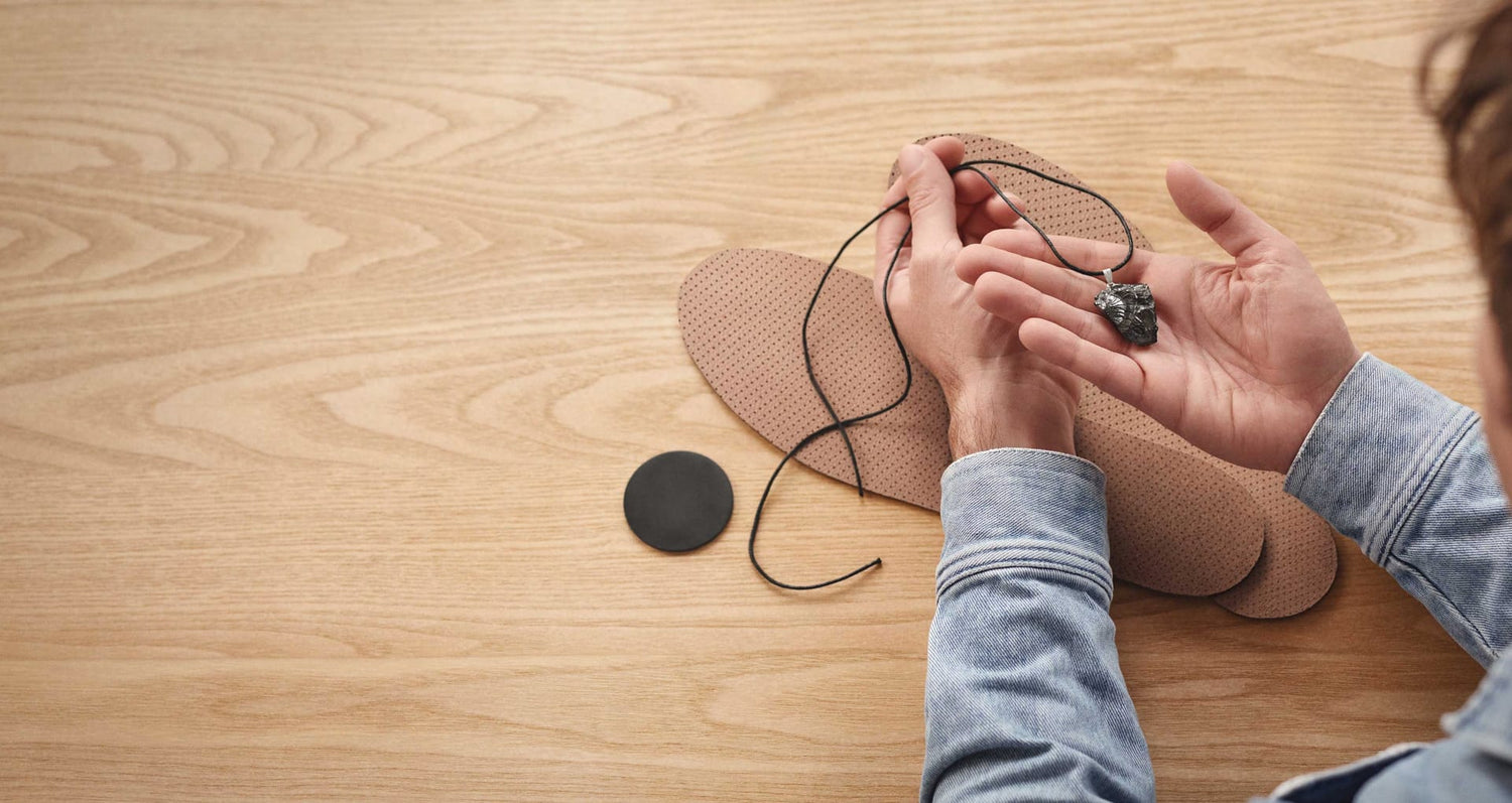 Unboxing-Situation des Beyond Matter Essentials-Sets: Ein Anhänger wird in der Hand gehalten, die Einlegesohlen liegen auf dem Tisch.