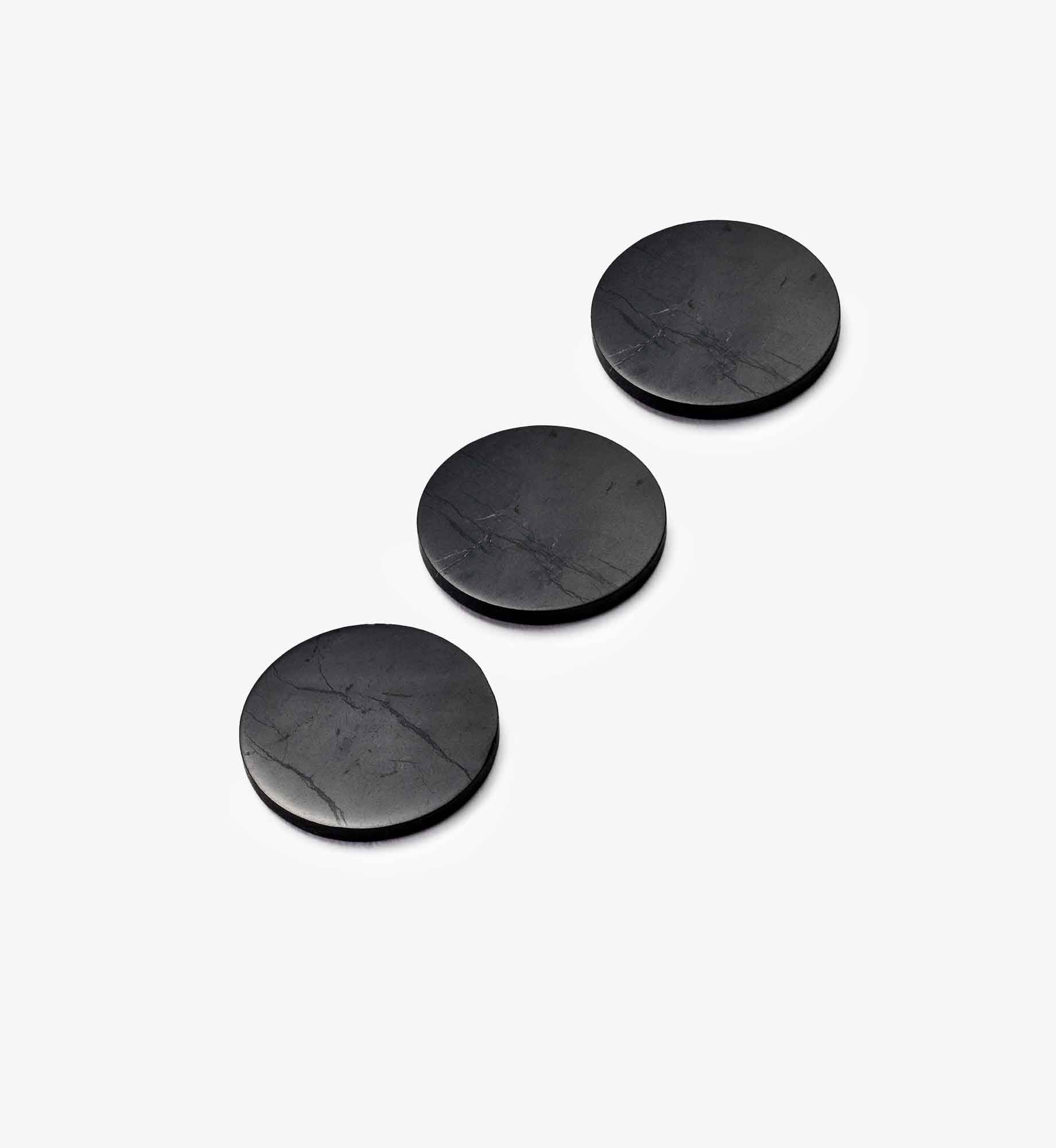 Drei runde Chips Stella aus EssenceX-Schungit von Beyond Matter auf hellem Hintergrund.