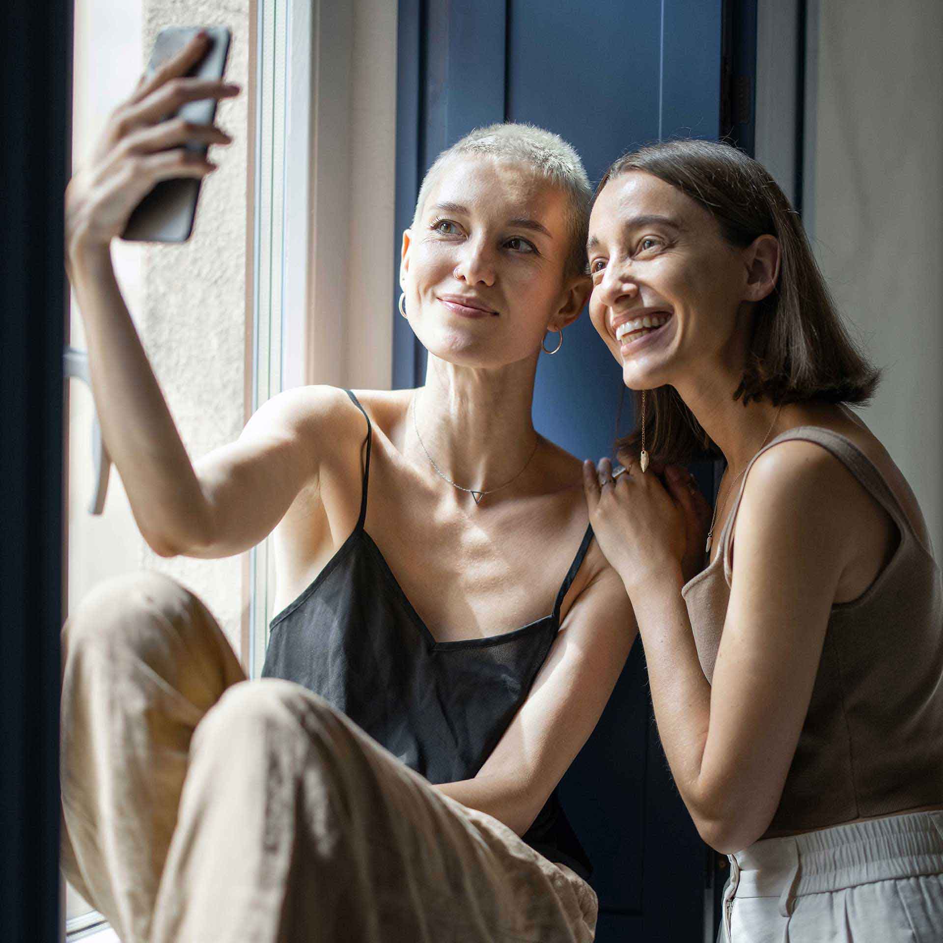 Zwei Frauen machen ein Selfie – Sinnbild für unbeschwerte Verbindung im digitalen Alltag.