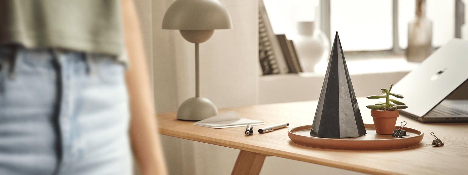 Schungit-Pyramide auf einem aufgeräumten Schreibtisch im Homeoffice – Beispiel für harmonische Integration von Technologie, Design und EMF-Schutz im Alltag.