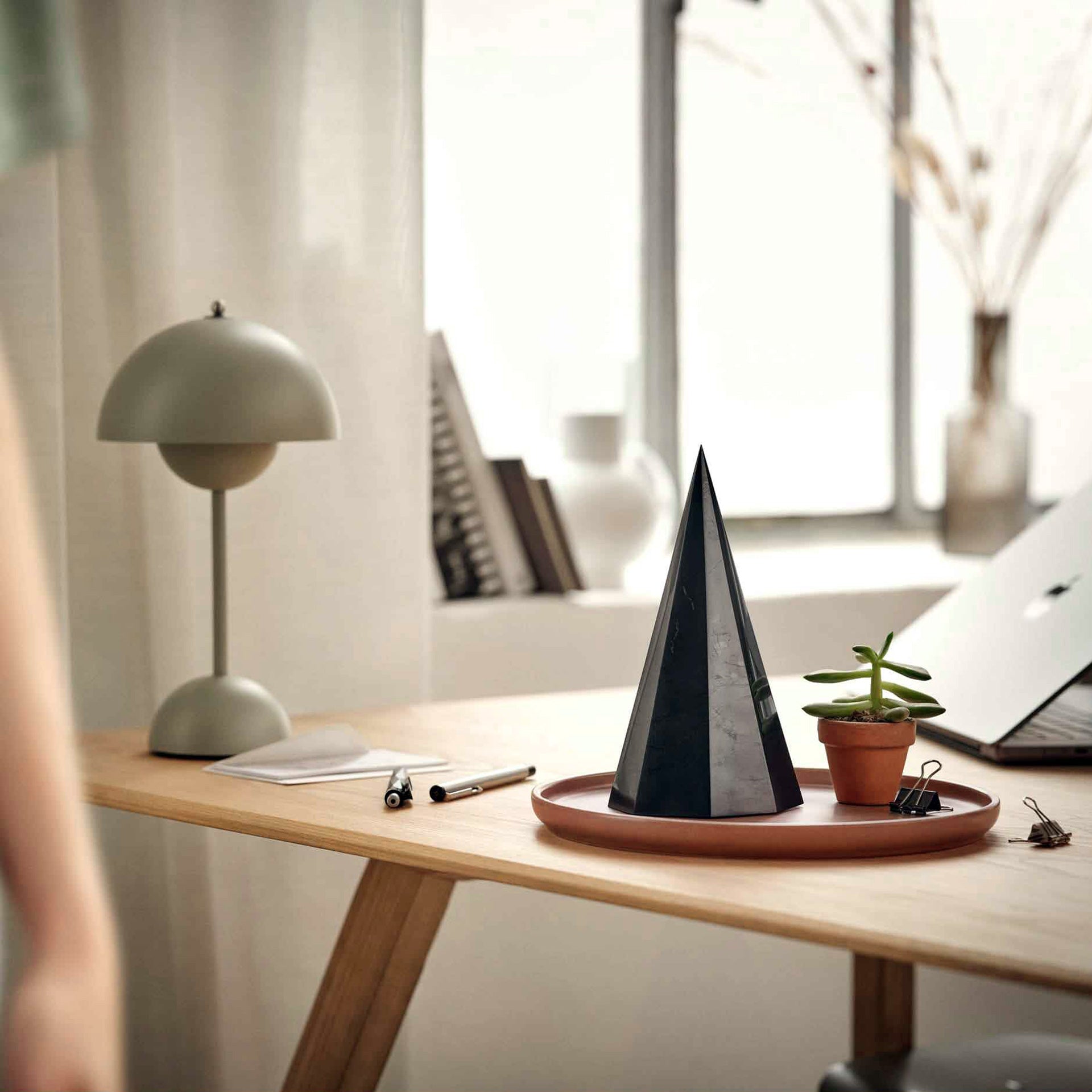 Schwarze Pyramide auf einem Schreibtisch – ruhige Präsenz im Arbeitsraum.