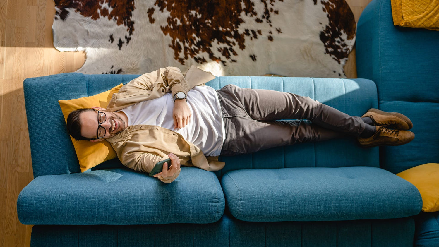 Mann liegt auf dem Sofa – visuelle Darstellung von einer intensiven Handynutzung im Alltag.