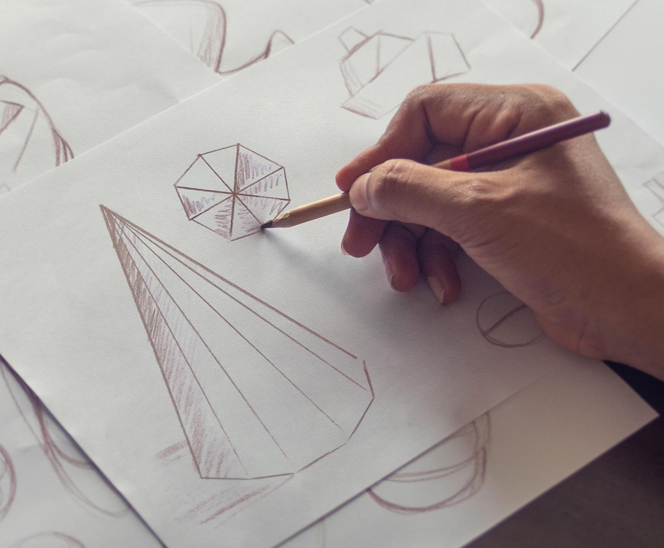 Hand zeichnet geometrische Formen und Prototypen – Sinnbild für Entwicklung, Forschung und den Ursprung der Beyond-Matter-Technologie.