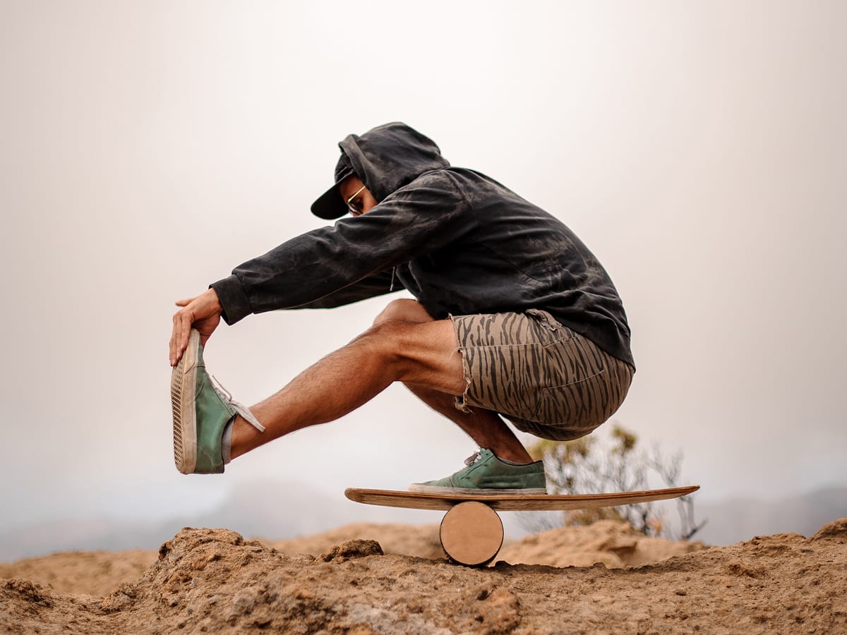 Mann balanciert auf einem Board im Freien – Sinnbild für Bewegung, Körpergefühl und Ausgleich.