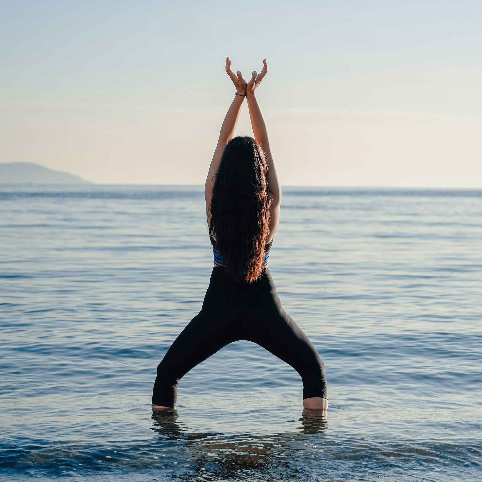 Frau im Wasser mit erhobenen Armen – Sinnbild für Lebendigkeit, Energie und natürliche Verbindung im Alltag.